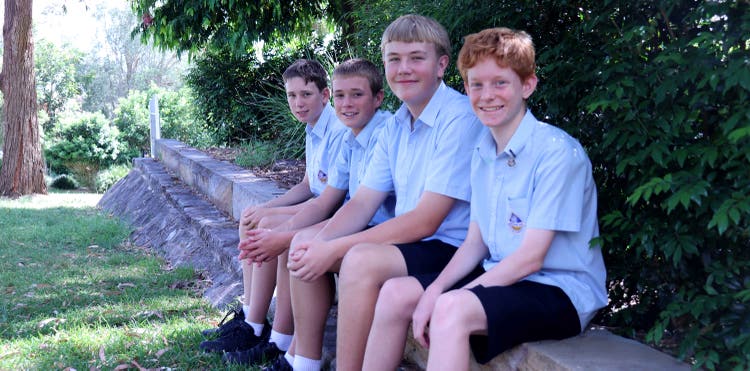 Smiling students sitting on wall
